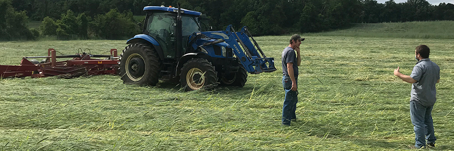 Image of two people standing in a field with a tractor